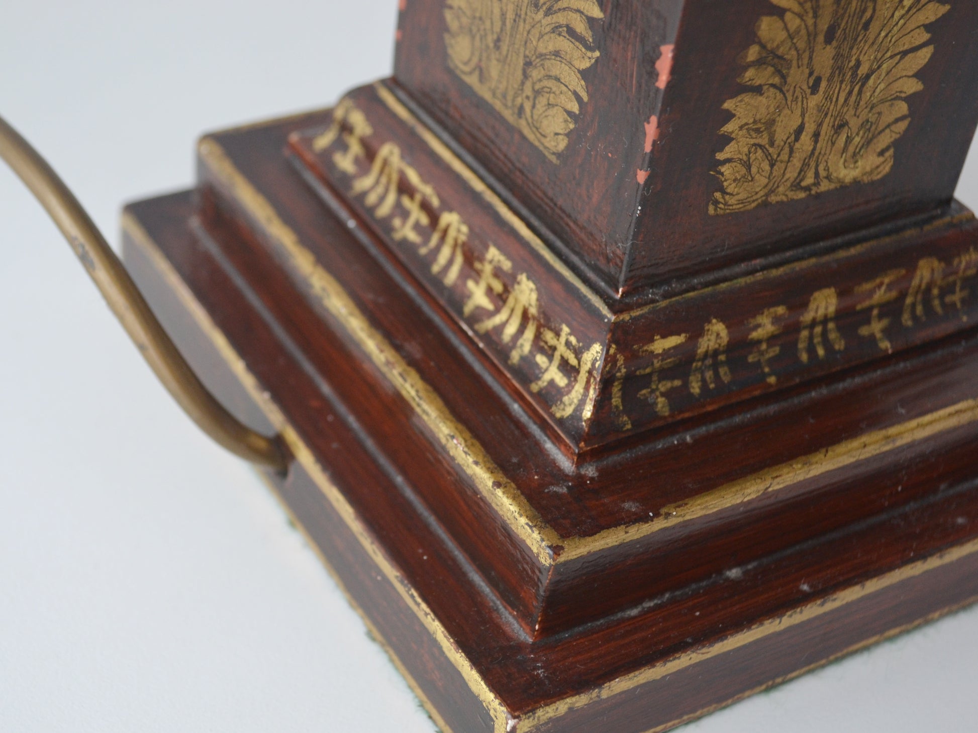 Gilt acanthus panel decoration on stepped square plinth of French Empire lacquered wood column lamp, close-up