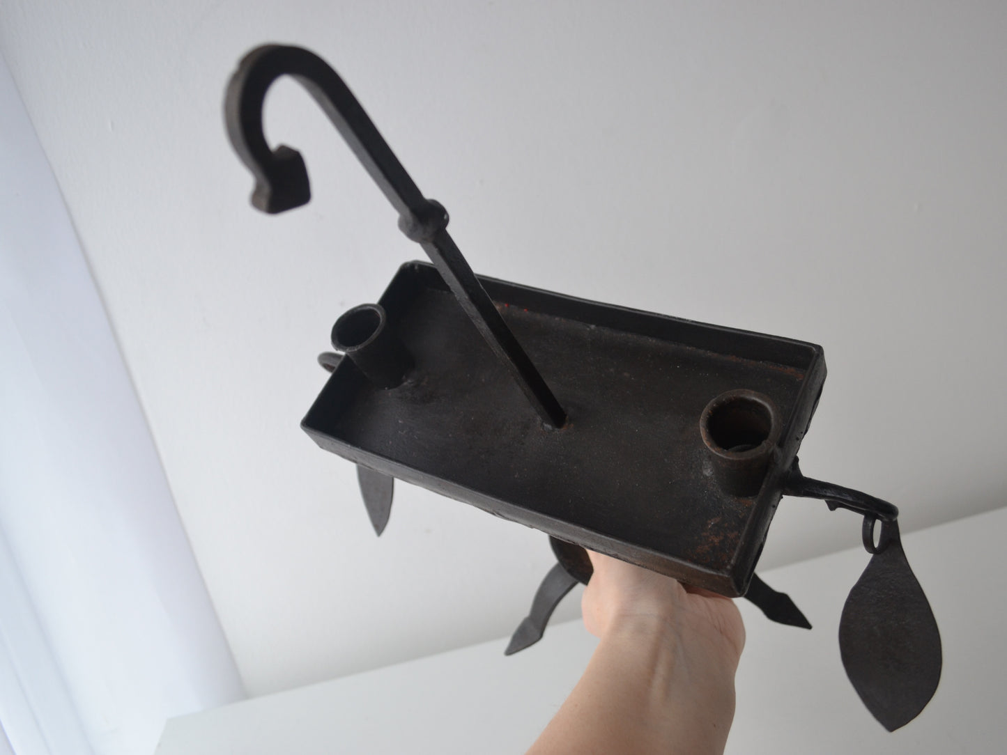 Hand-forged wrought iron candle stand shown with hand for scale, Arts & Crafts style, leaf pendant detail