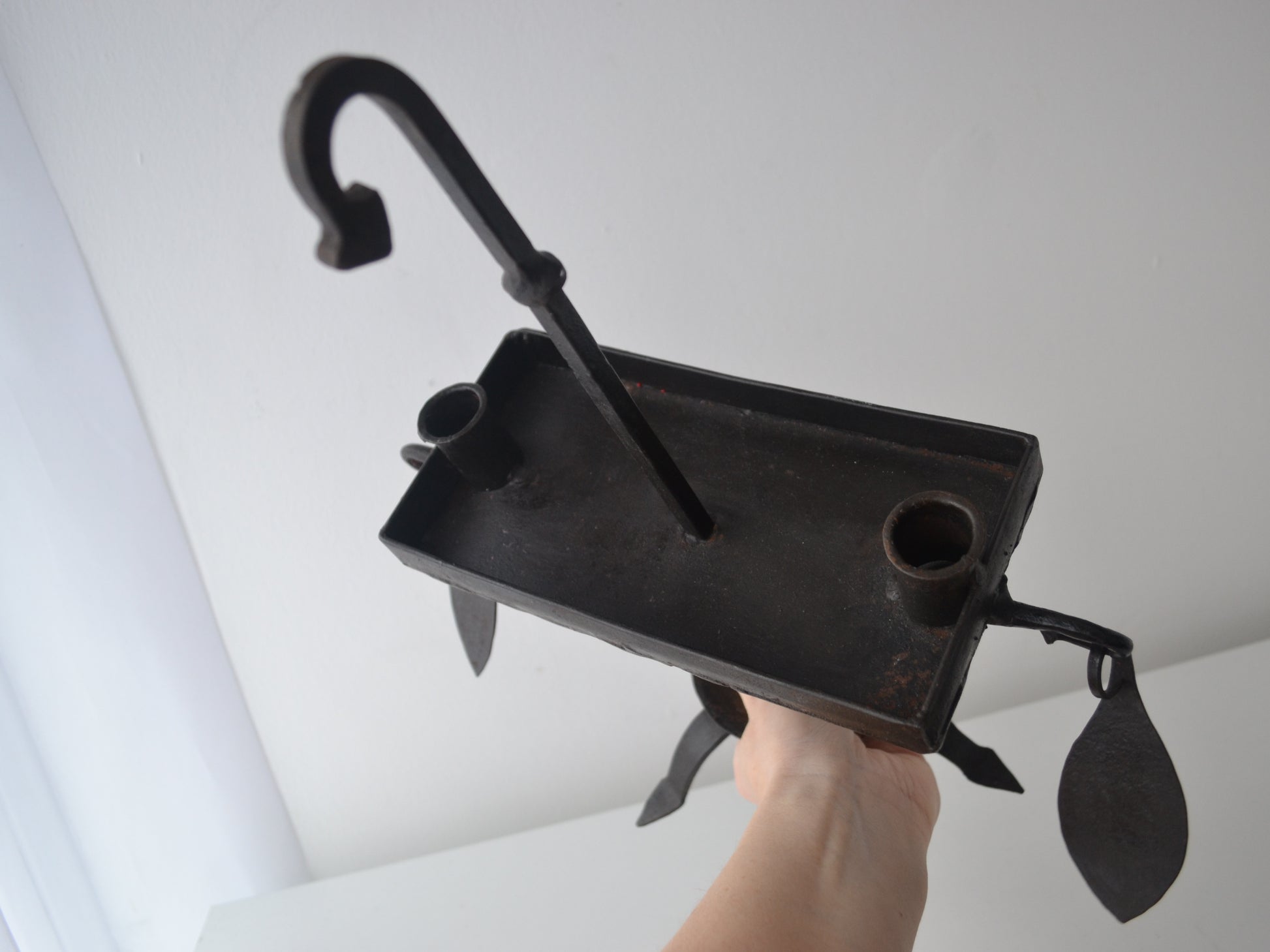 Hand-forged wrought iron candle stand shown with hand for scale, Arts & Crafts style, leaf pendant detail