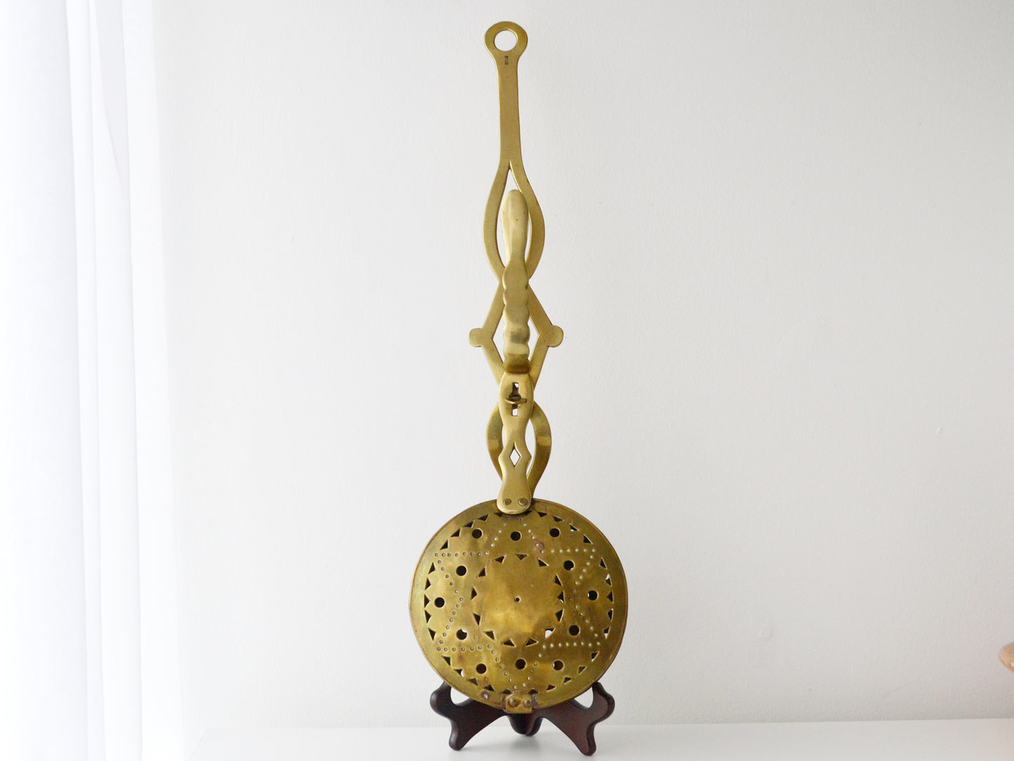Brass Victorian chestnut roaster, pierced star pattern, England circa 1900s, front view on display stand.