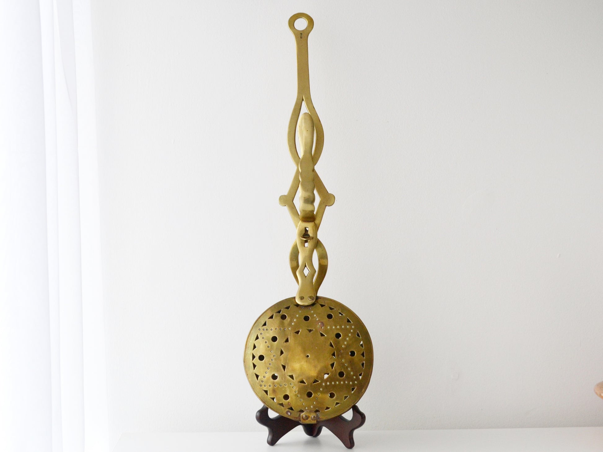 Brass Victorian chestnut roaster, pierced star pattern, England circa 1900s, front view on display stand.