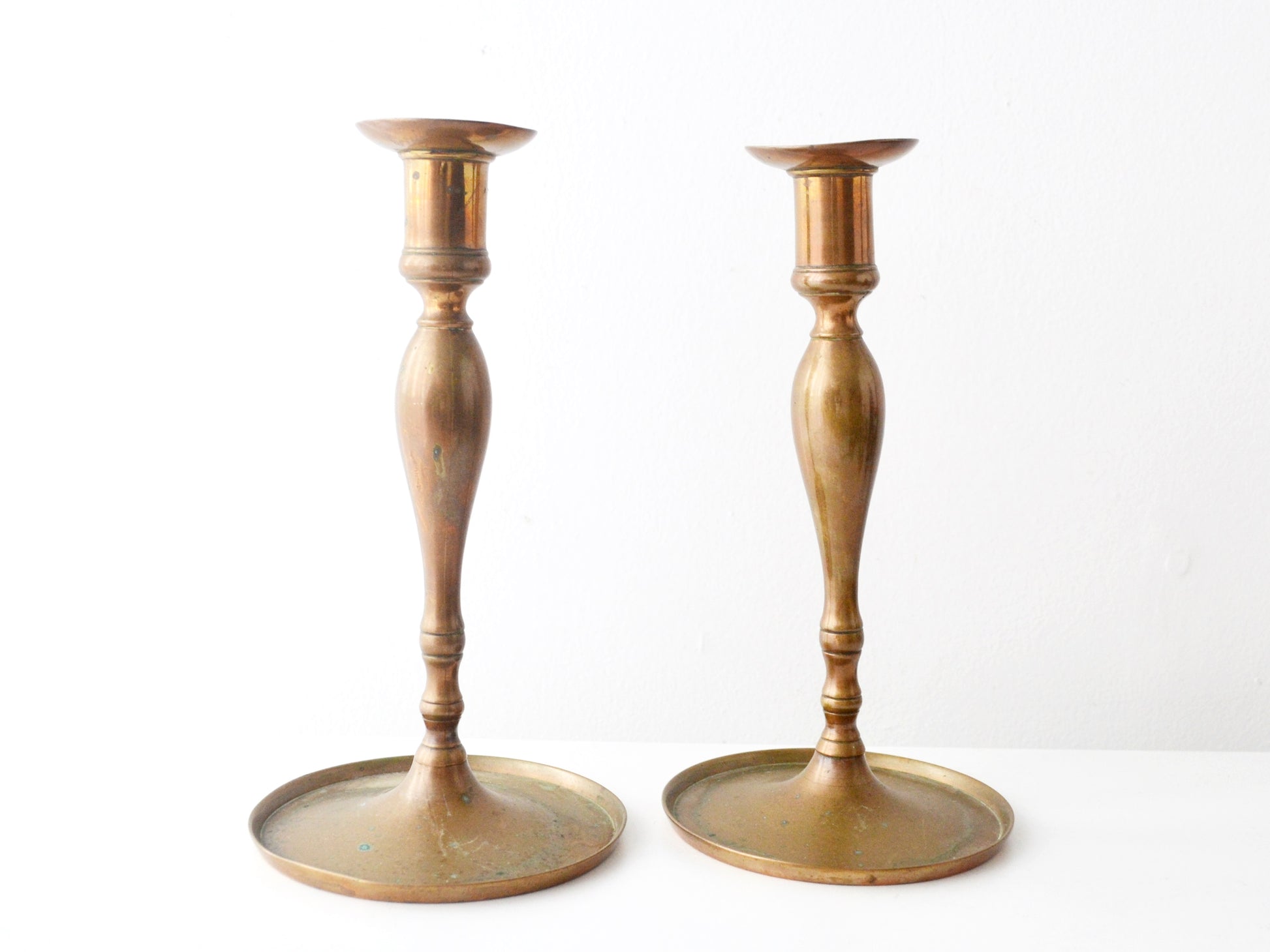 Antique brass candlestick pair, hand-cast baluster column, wide circular base, Europe circa 1780–1840, front view