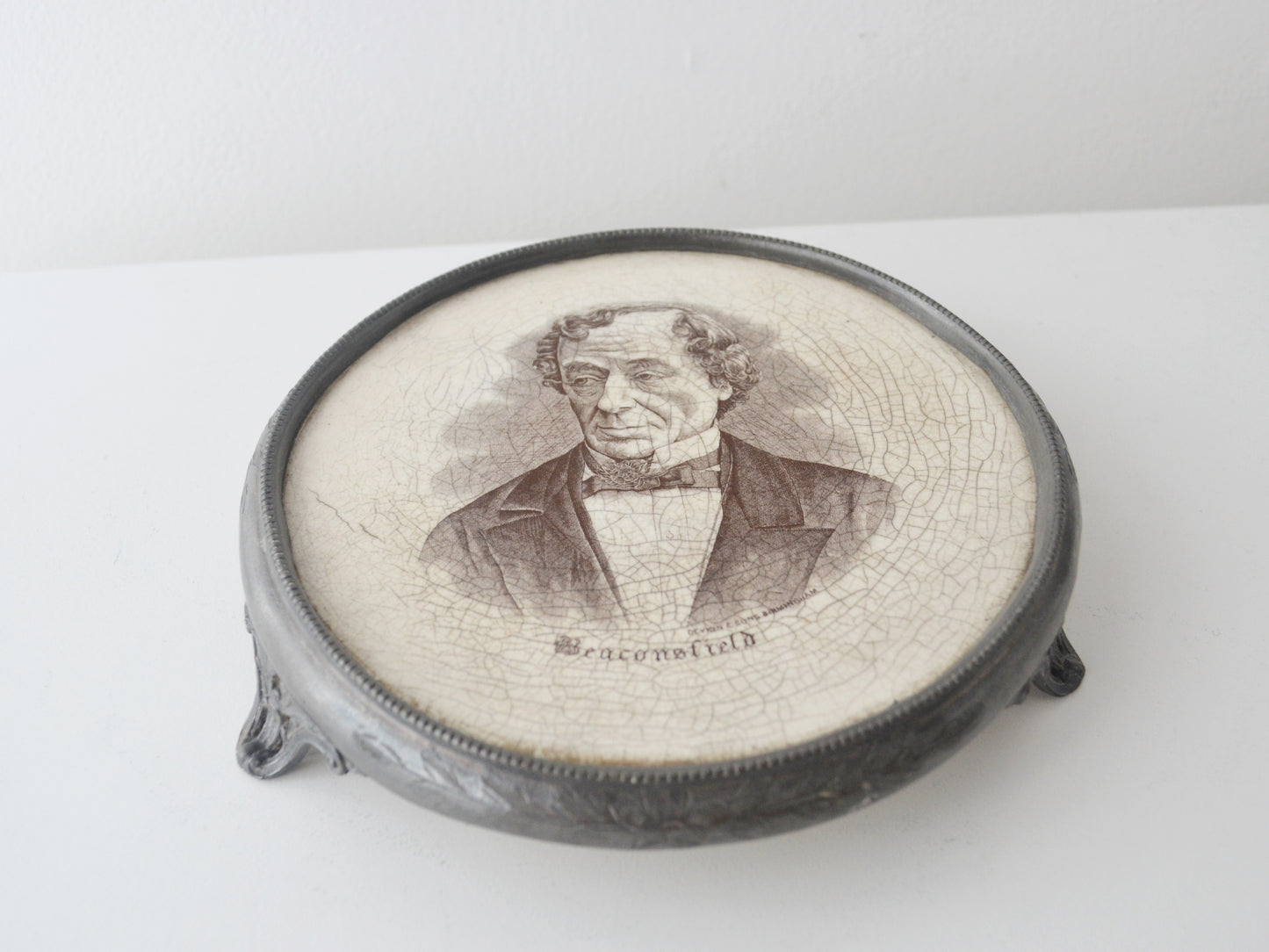 Victorian Disraeli commemorative teapot stand, Deykin &amp; Sons Birmingham circa 1881, black transfer portrait, beaded white metal frame, brass feet, front view