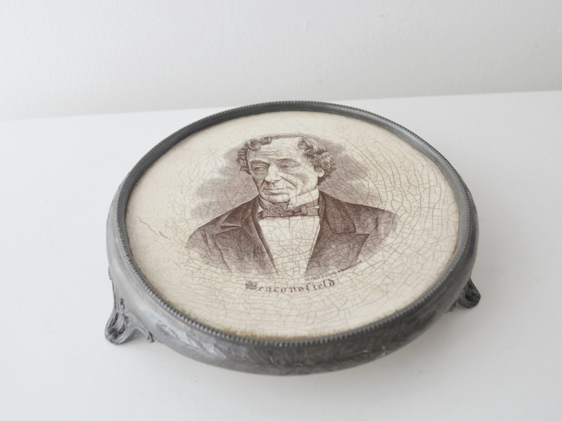 Victorian Disraeli commemorative teapot stand, Deykin &amp; Sons Birmingham circa 1881, black transfer portrait, beaded white metal frame, brass feet, front view
