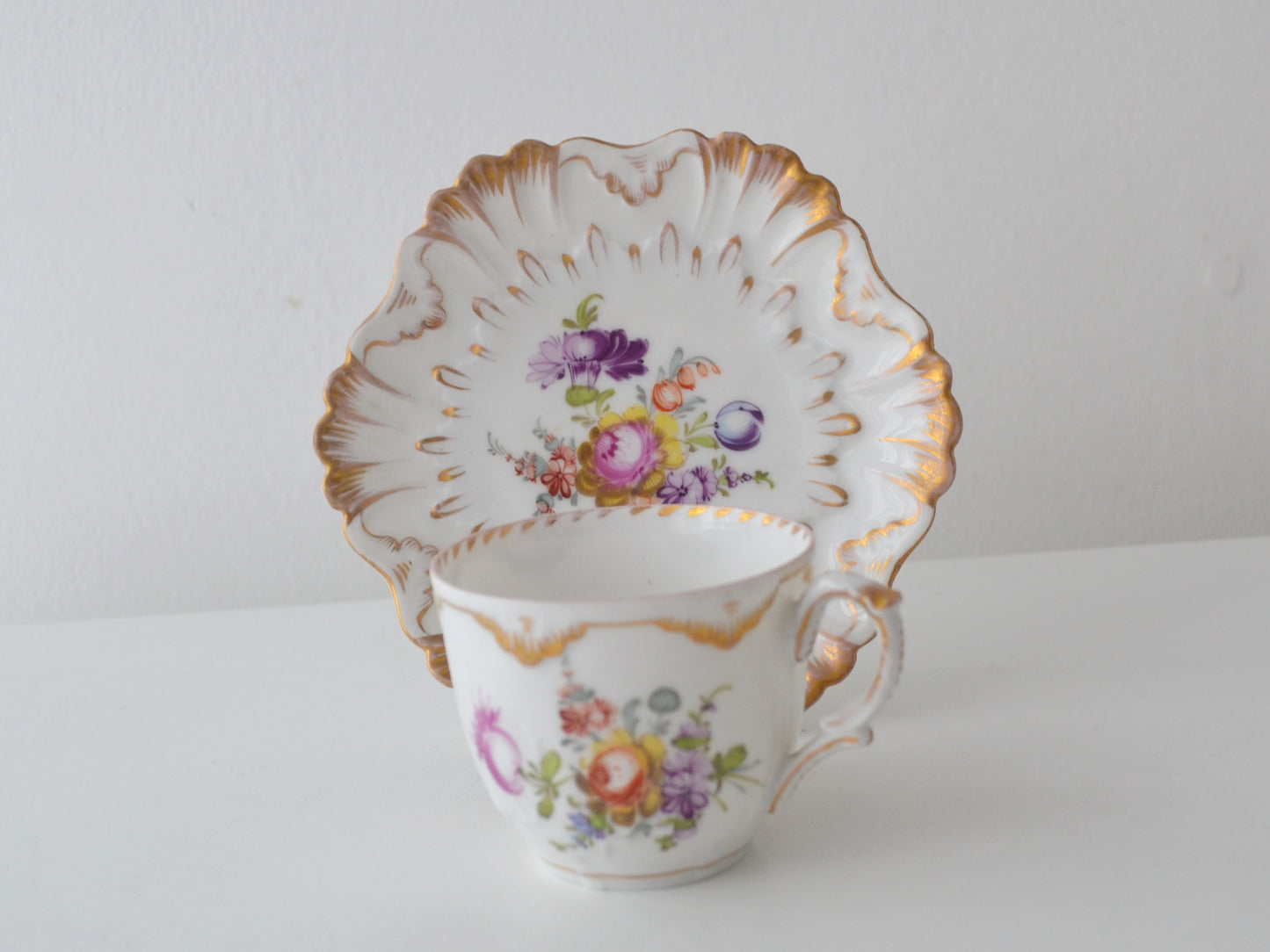 Dresden porcelain cup and saucer, R. Grossbaum &amp; Söhne circa 1892–1914, hand-painted floral bouquet, shell-relief moulding, gilded rococo edge, front view