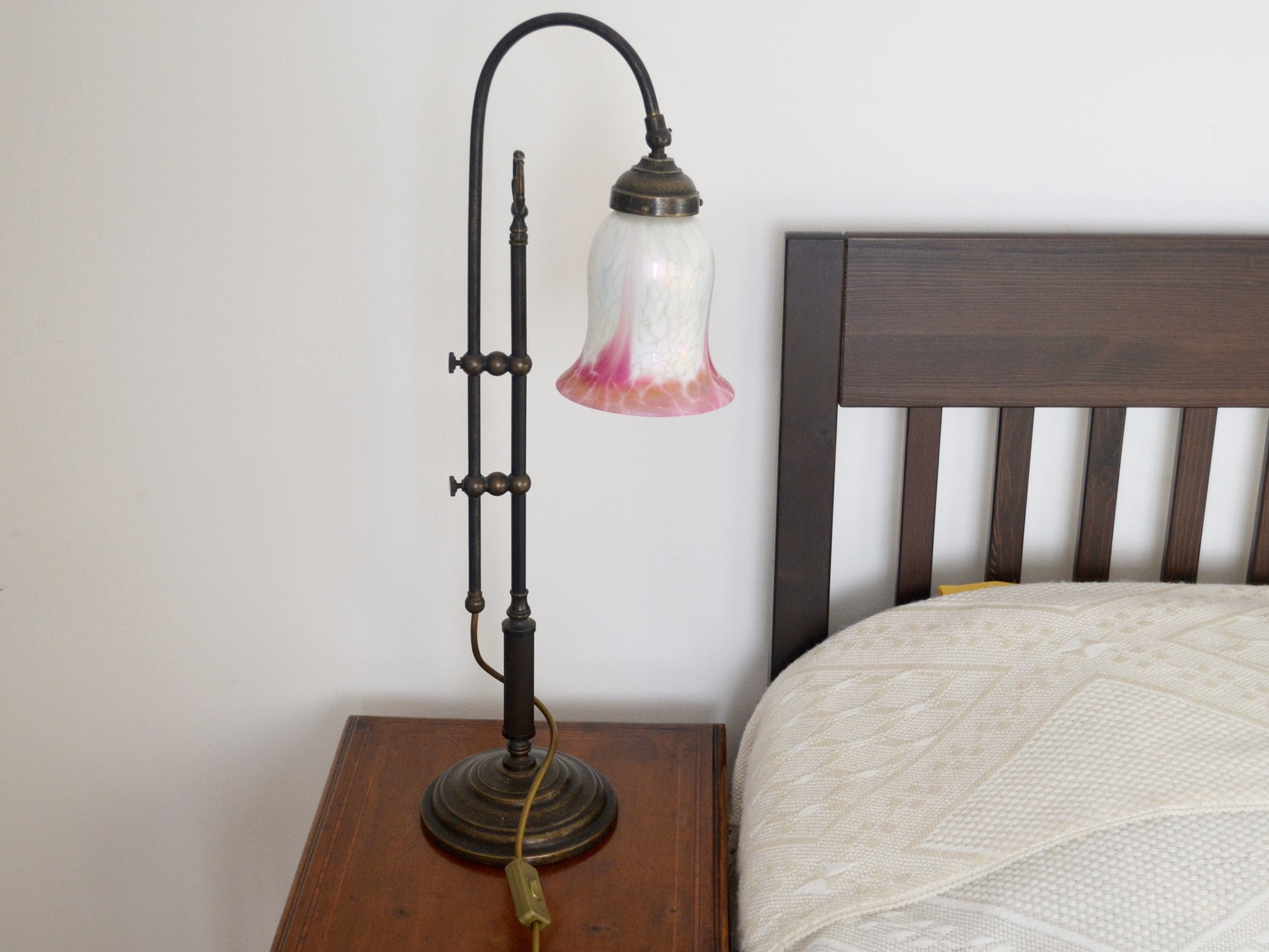 Adjustable brass swan neck table lamp with hand-blown opaline glass tulip shade, white with pink gradient, front view.