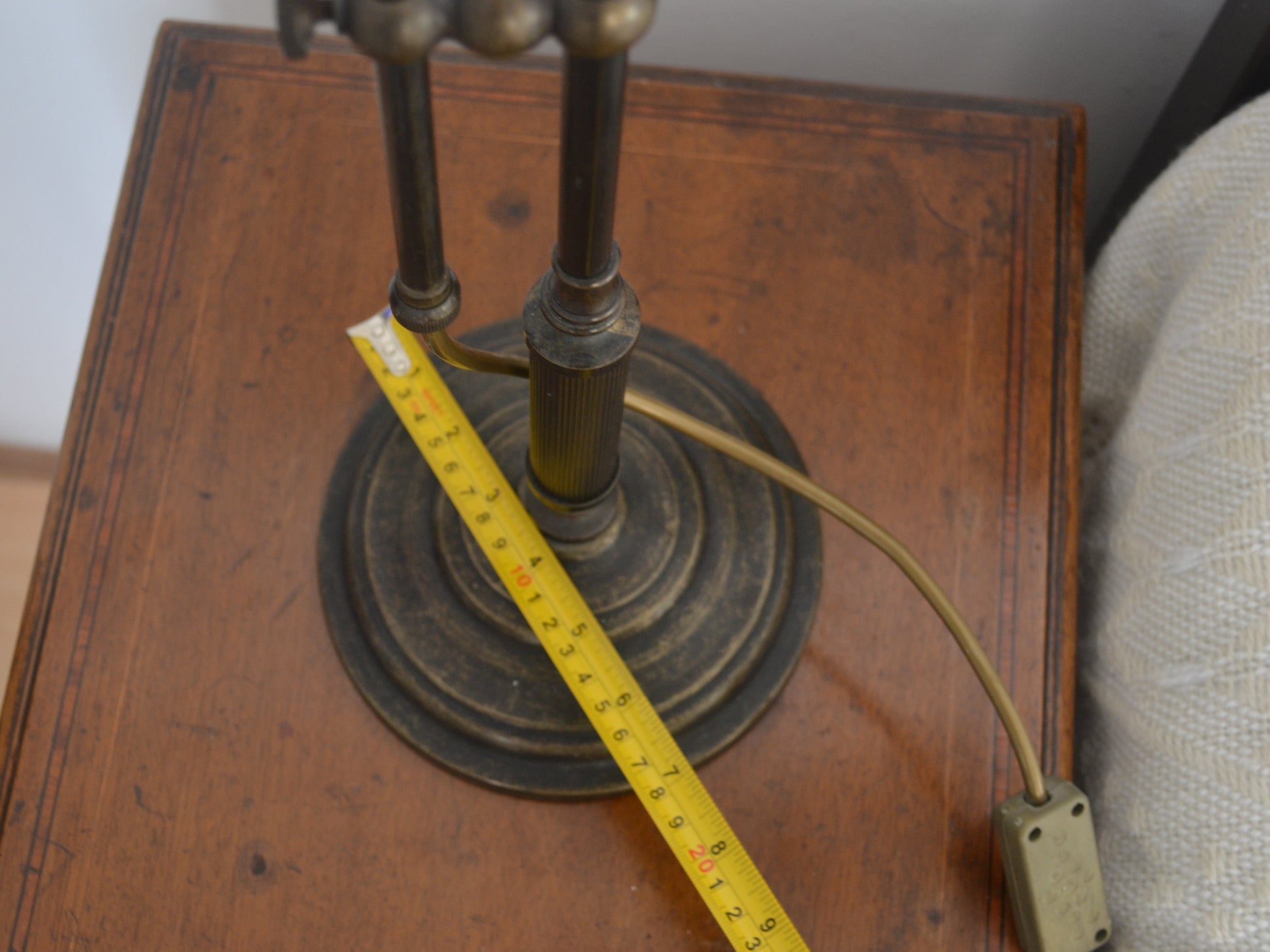 Circular stepped base of brass swan neck table lamp showing patinated finish, detail view.