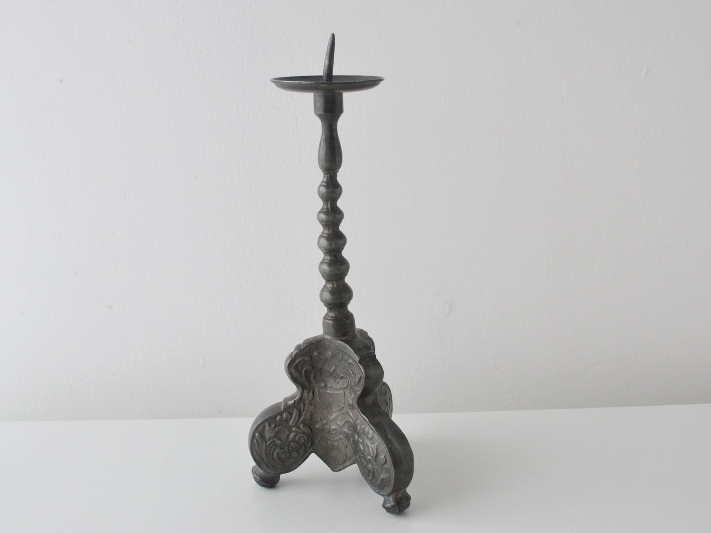 Repousse acanthus and cartouche decoration on tripod base of baroque pewter candlestick.