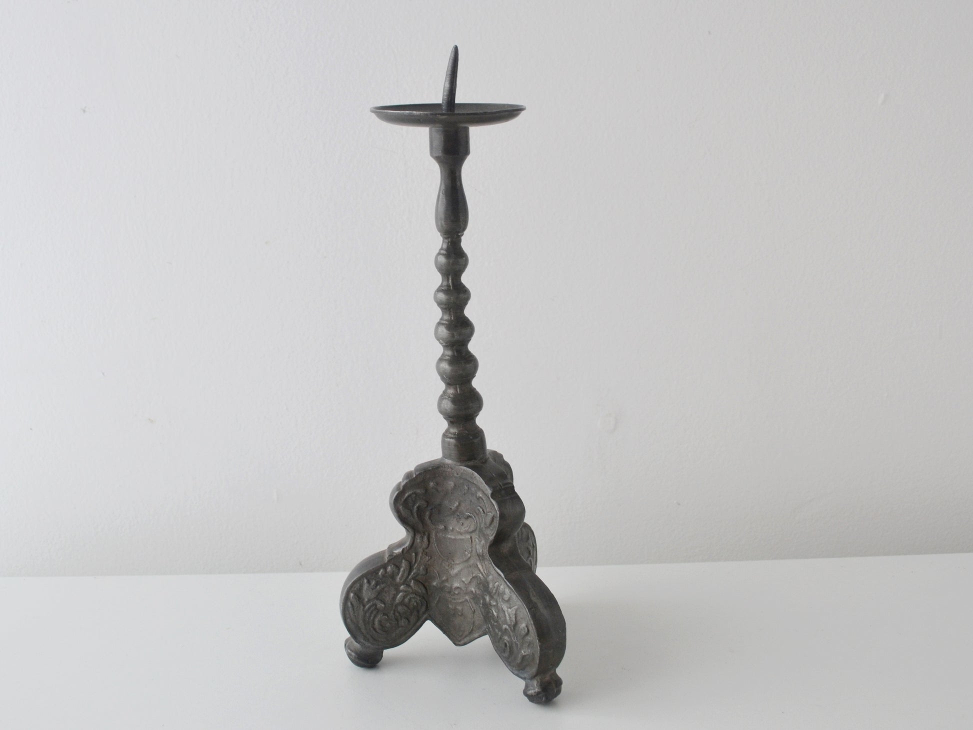 Repousse acanthus and cartouche decoration on tripod base of baroque pewter candlestick.