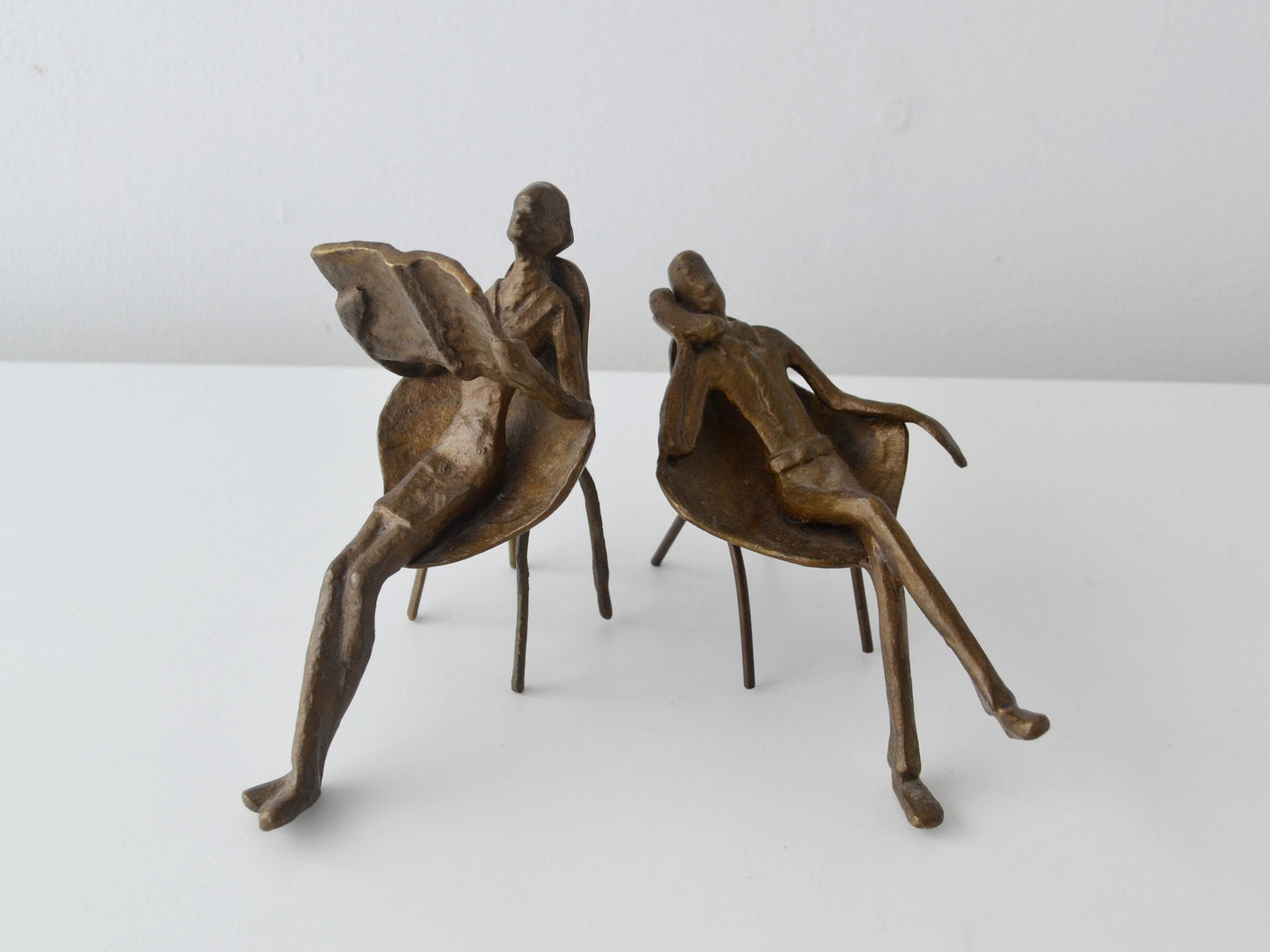 Cast bronze pair of seated figures, woman reading newspaper and man on telephone, tulip chairs, Mid-Century Modern Europe circa 1960s, front view