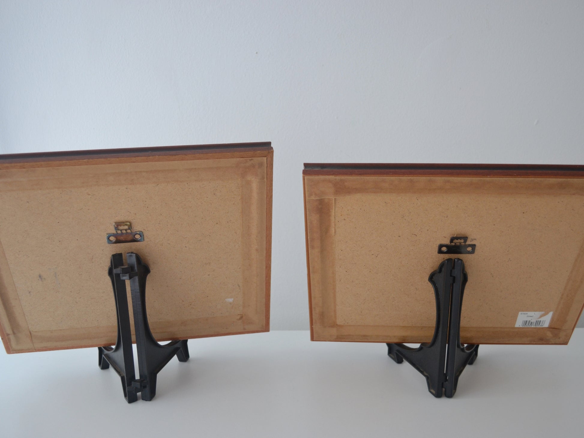 Reverse of vintage framed L.S. Lowry prints showing picture hanger hardware.