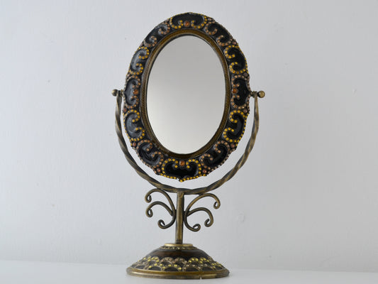 Brass and bronze enamel tilting vanity mirror on scrollwork pedestal stand, rhinestone-set frame, India circa 1960s, front view
