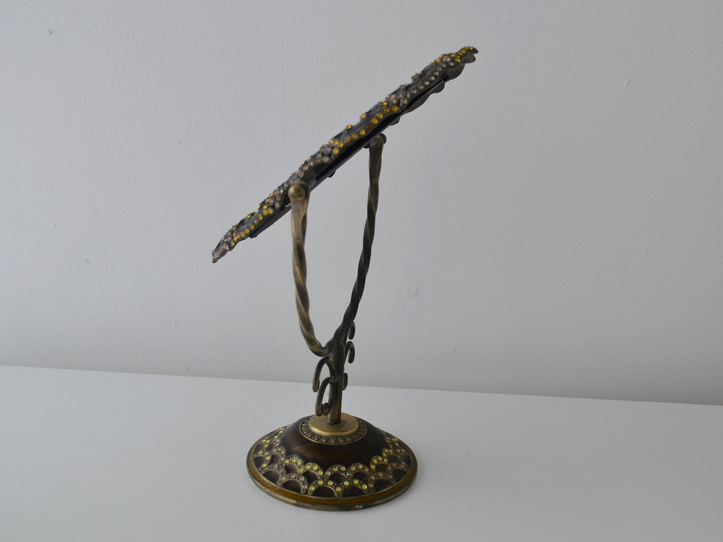 Brass enamel vanity mirror on twisted wire stand, tilted side view showing scrollwork upright and domed base, India circa 1960s