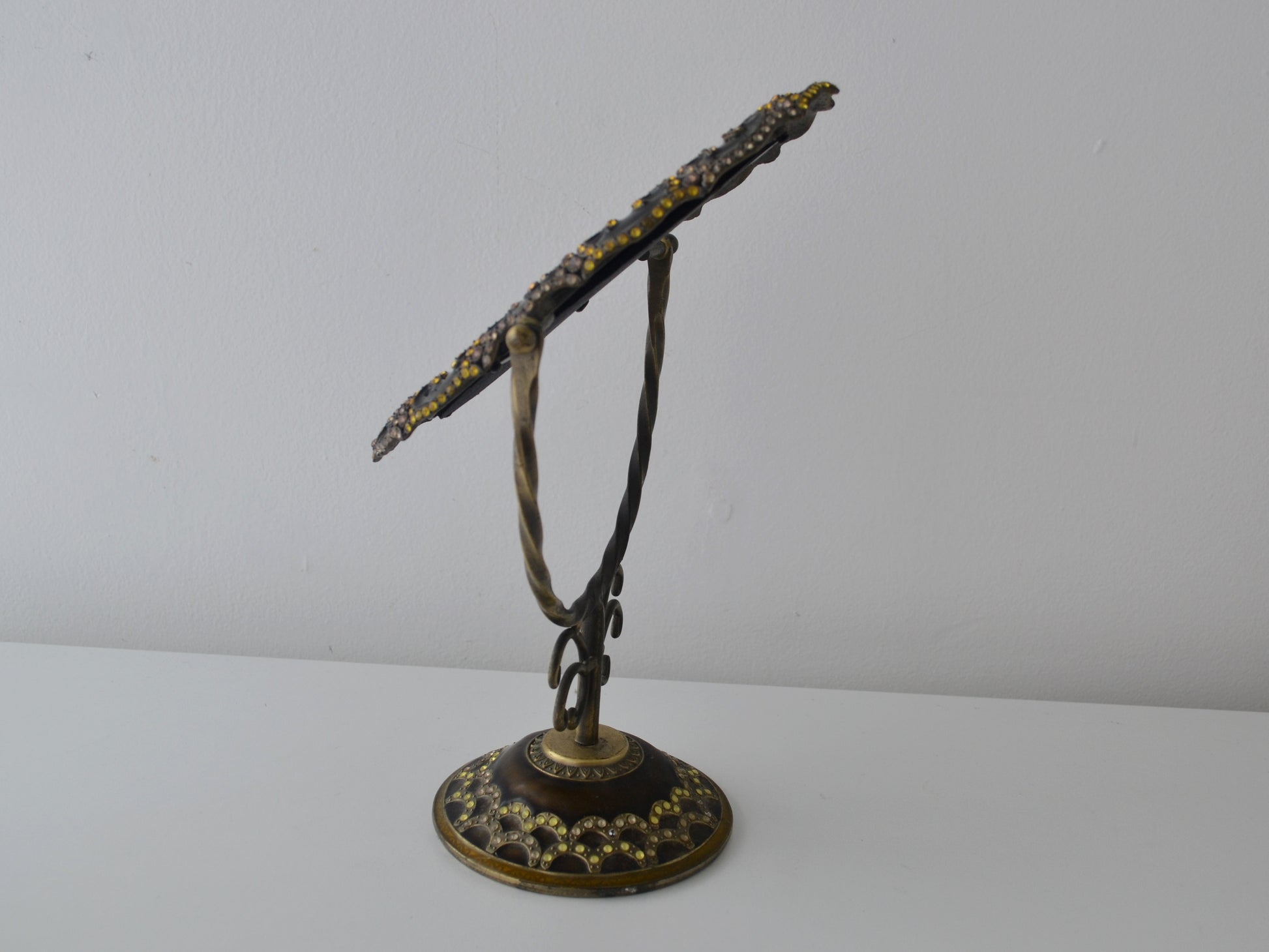 Brass enamel vanity mirror on twisted wire stand, tilted side view showing scrollwork upright and domed base, India circa 1960s