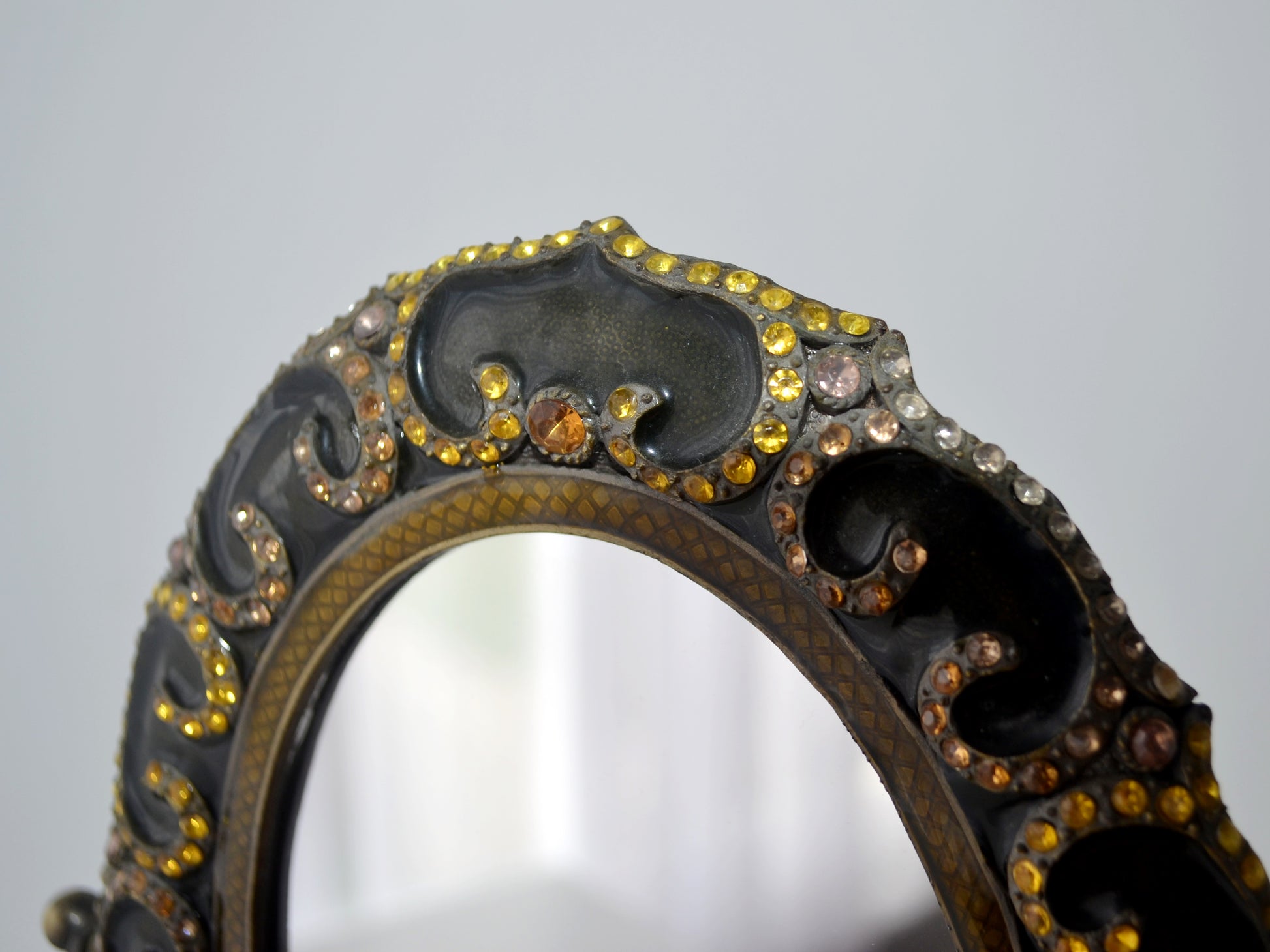 Brass enamel oval vanity mirror on pedestal, three-quarter view showing rhinestone frame and scrollwork stand, India circa 1960s