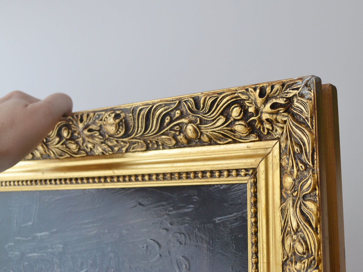 Detail of ornate carved gilt frame, floral relief pattern, vintage decorative print.