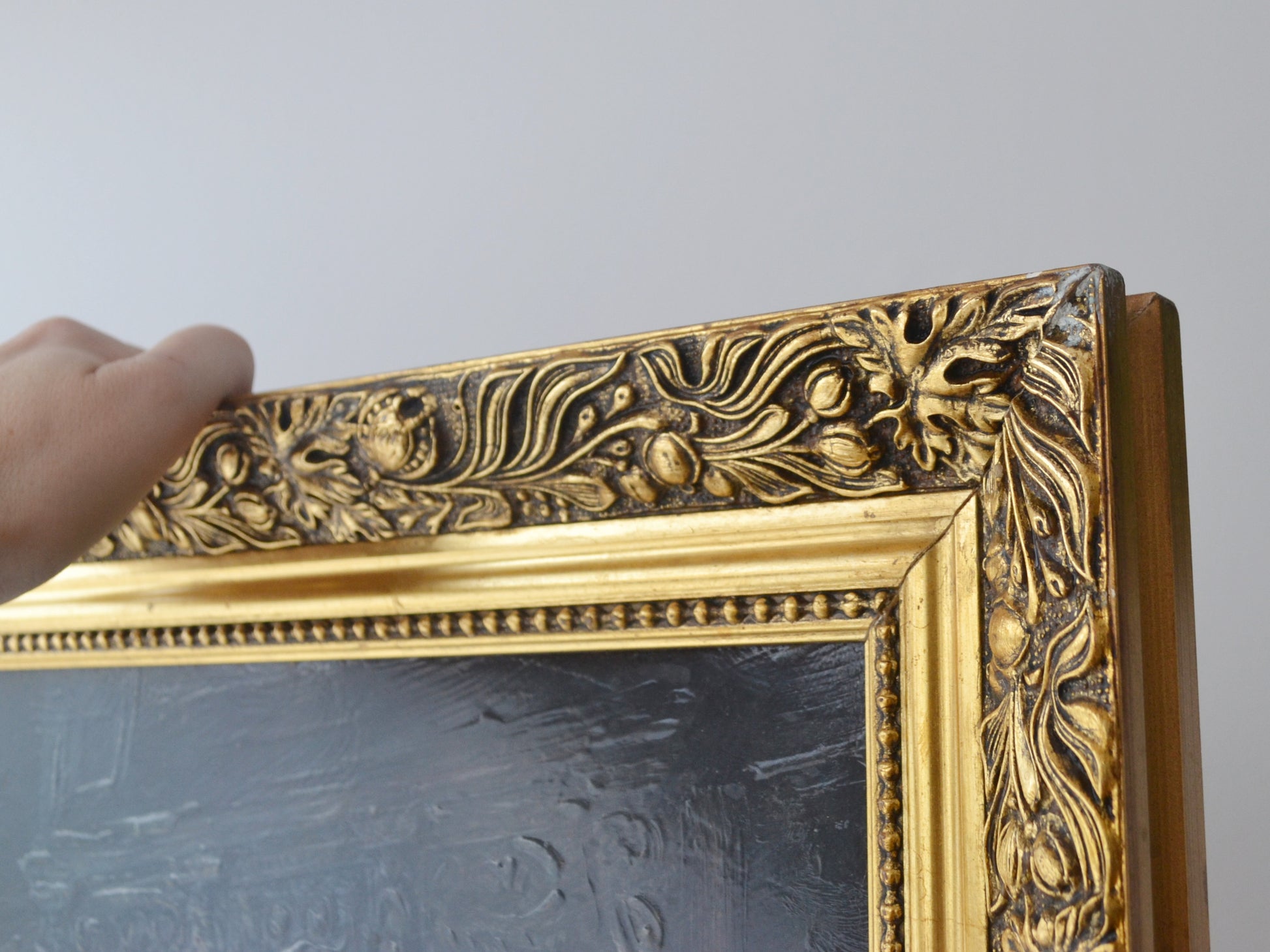 Detail of ornate carved gilt frame, floral relief pattern, vintage decorative print.