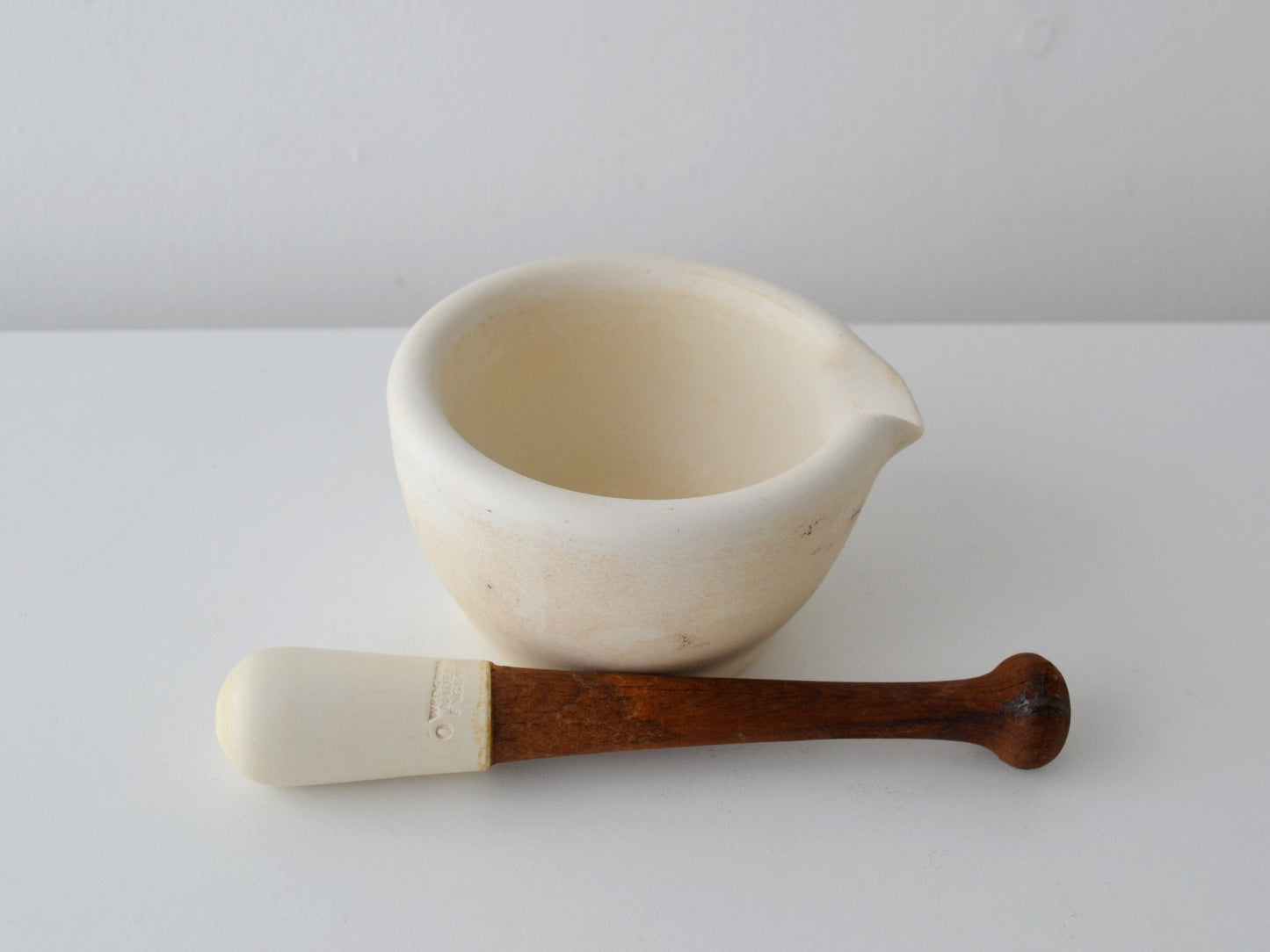 Wedgwood composition mortar with wooden pestle, side view showing lipped pouring spout and turned handle, England circa 1900