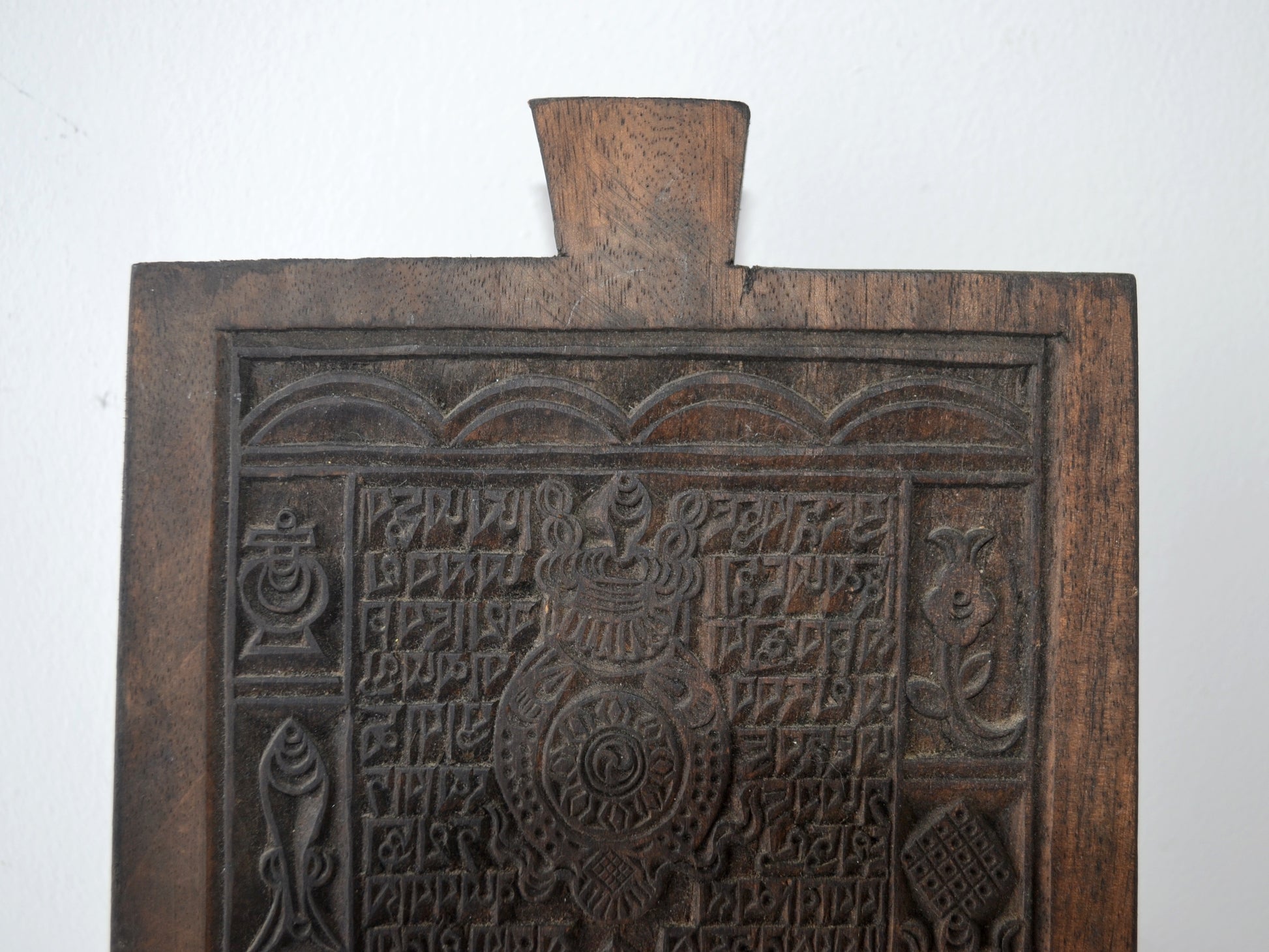 Detail of Tibetan woodblock carving showing Uchen script columns and Ashtamangala border symbols, circa 19th century