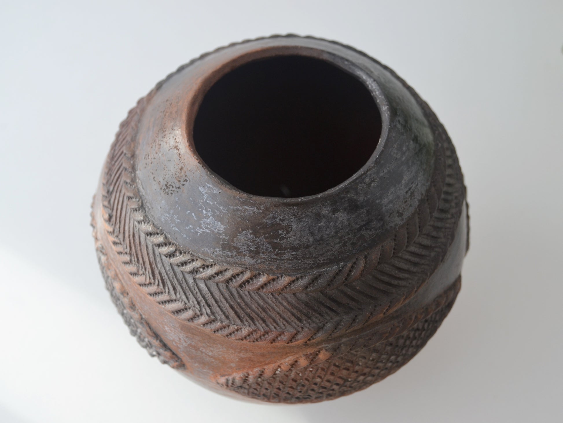 Signed Zulu ukhamba vessel by Mfeka in styled interior setting with foliage, smoke-fired earthenware South Africa