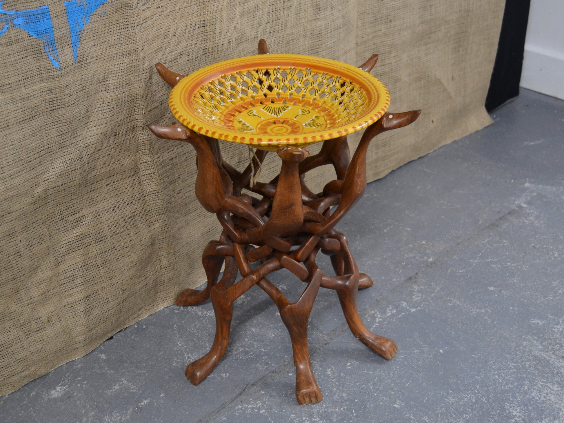 Hand-carved hardwood intertwined dog figures stand with Moroccan ceramic bowl, circa 1960s, side view.