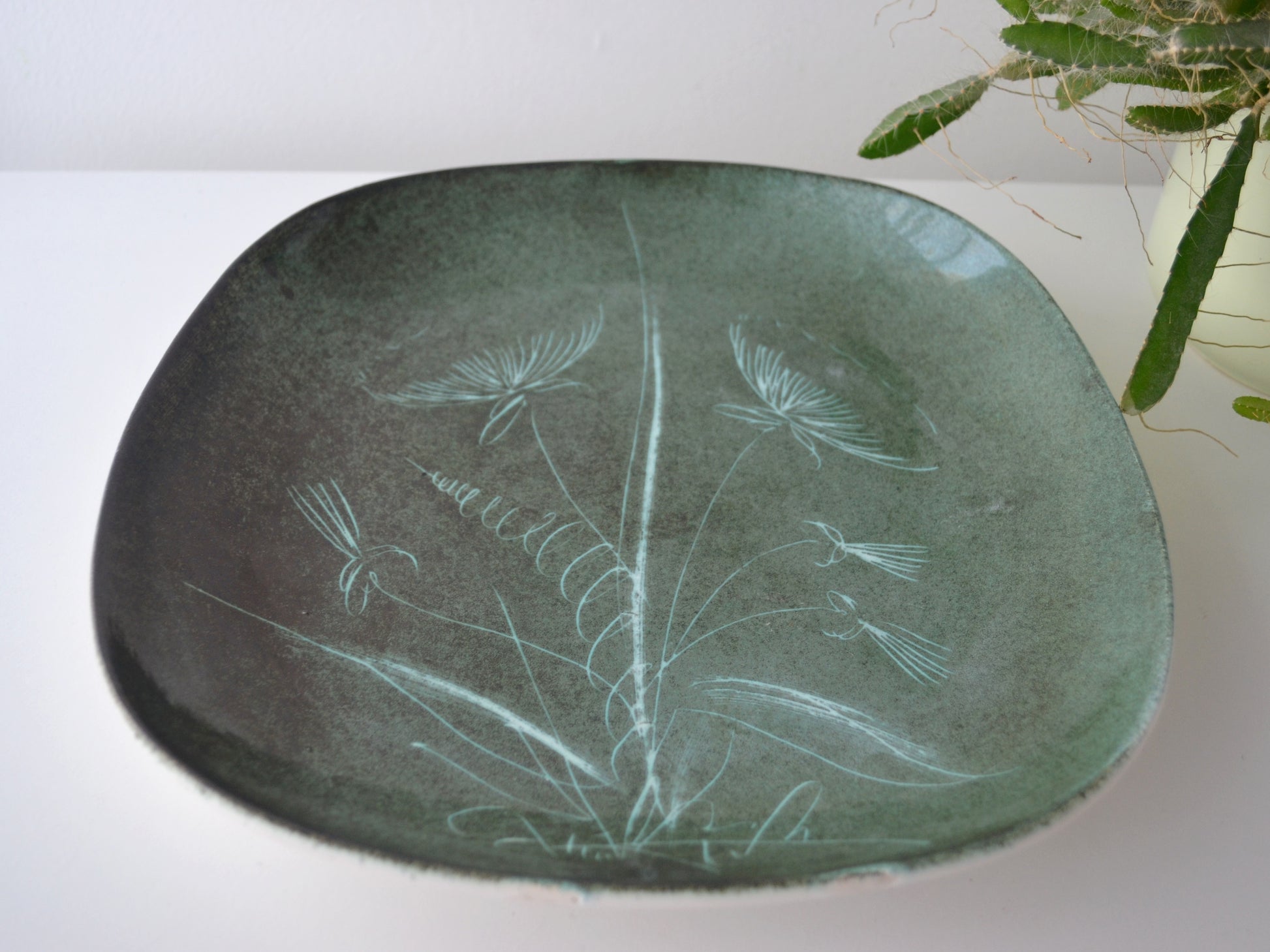 Rye Pottery sgraffito plate, side view showing footed base and rim, green glaze, circa 1950s