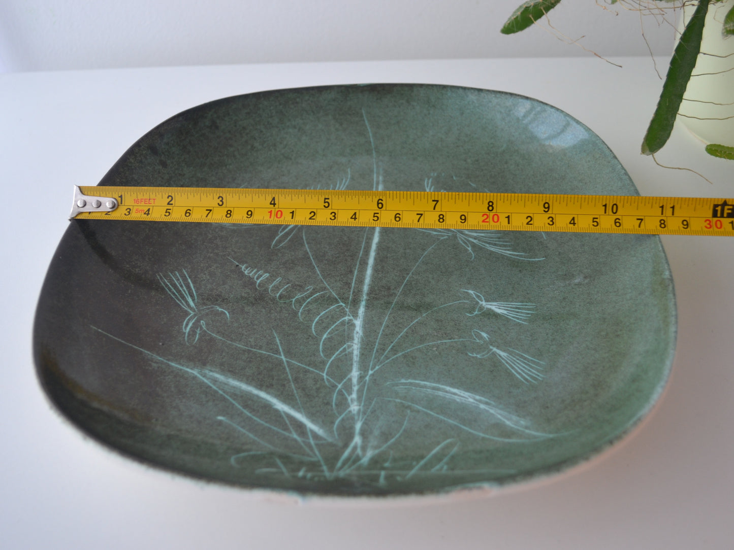 Rye Pottery sgraffito plate with tape measure showing 28cm diameter, botanical dandelion decoration